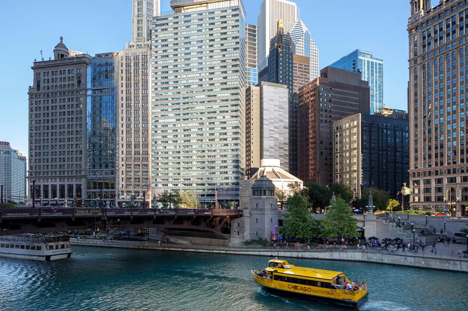 Chicago River waterfront with downtown skyline, bridges, and yellow tour boat
