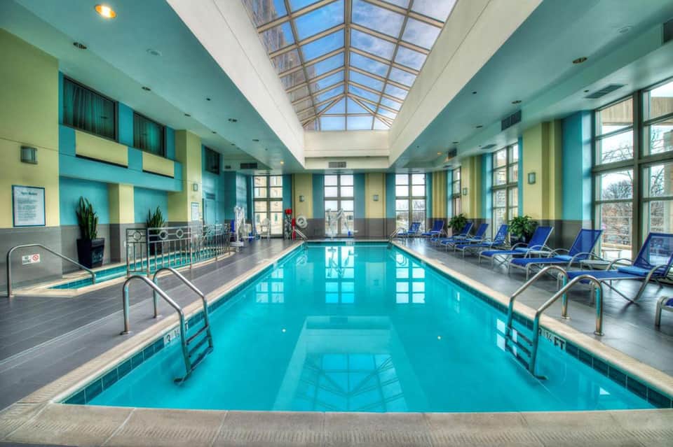 Indoor swimming pool with turquoise water, blue lounge chairs, skylights, and turquoise and yellow walls
