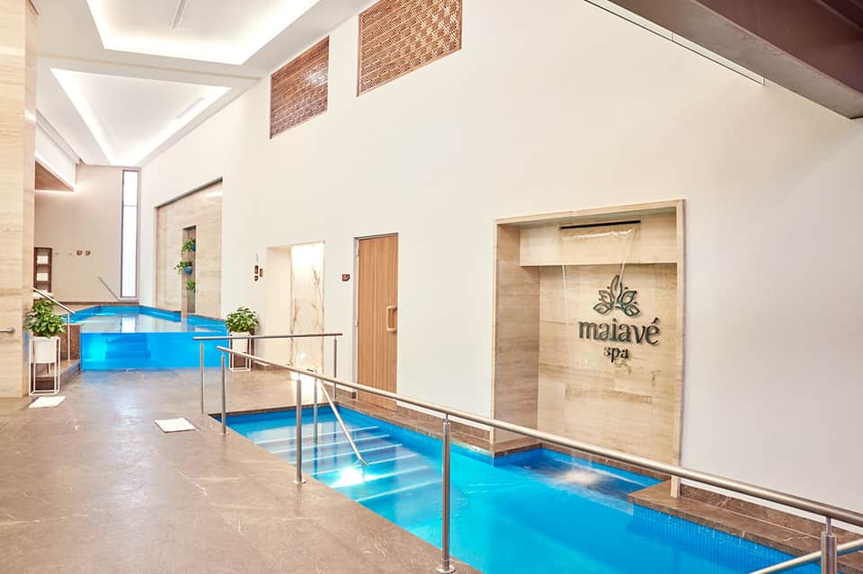 Modern indoor spa facility with illuminated blue water channels and Malave Spa entrance with wooden accents