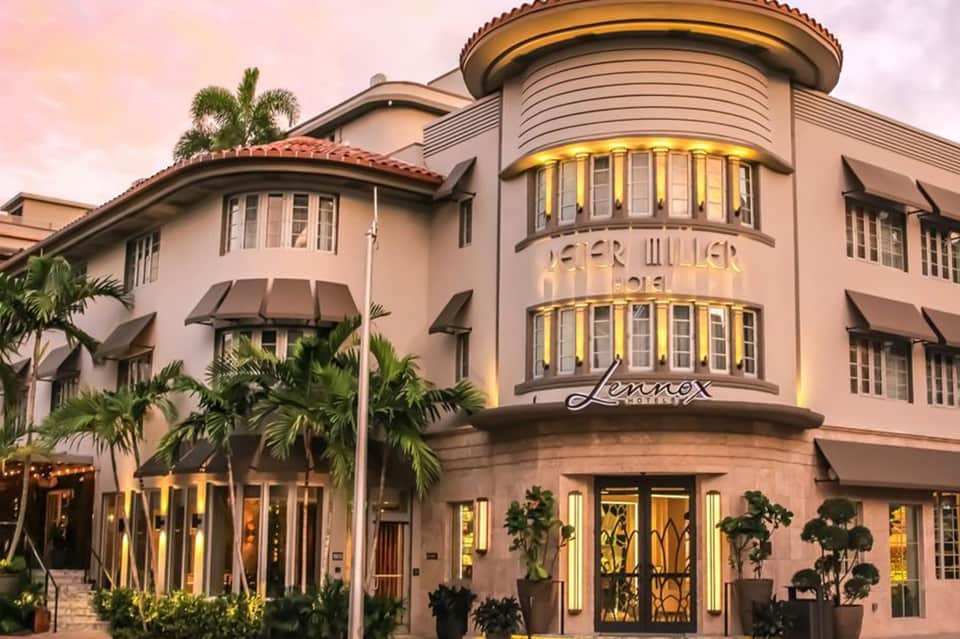 Historic pink Spanish-colonial style hotel building with curved tower and palm trees at dusk