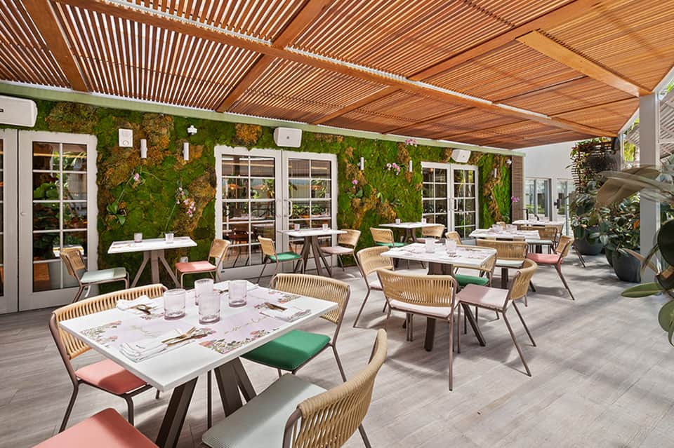 Outdoor fine dining patio with living green wall, wooden pergola, and woven chairs