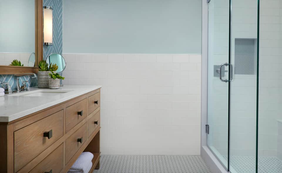 Modern bathroom with wooden vanity, white subway tile, glass shower enclosure and spa-like finishes
