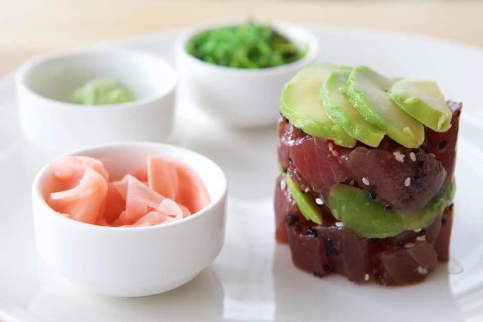 Tuna tartare tower with avocado, sesame seeds, pickled ginger, and wasabi condiments