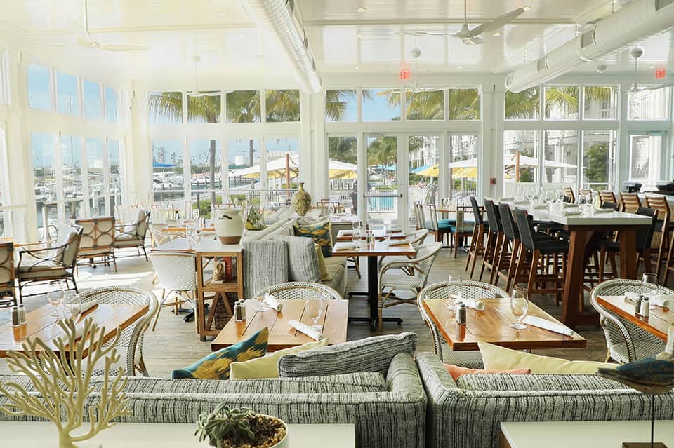 Bright beachfront dining room with floor-to-ceiling windows overlooking pool and beach areas