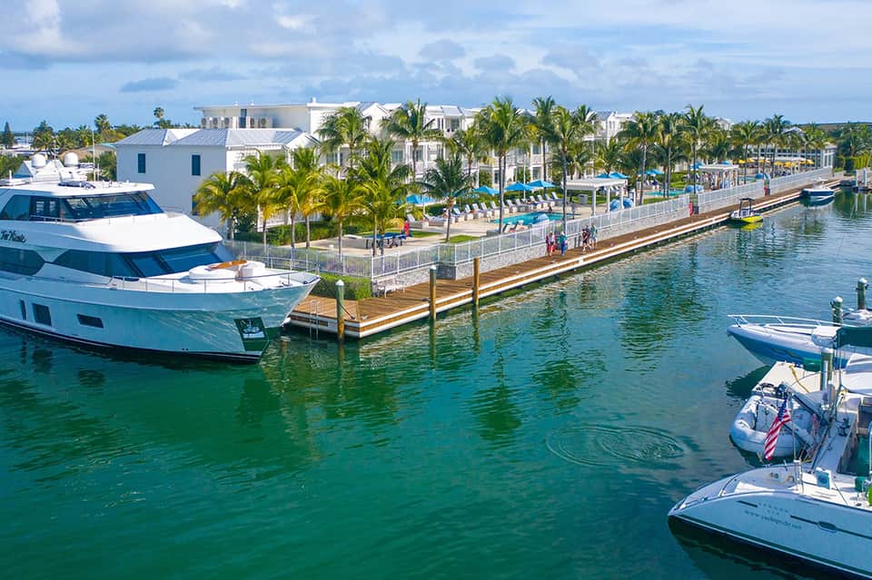 Waterfront marina with luxury yacht, boats, and white waterfront resort buildings