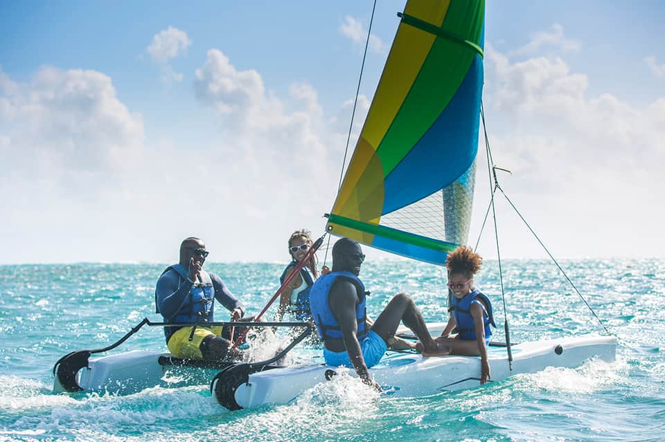Group of people sailing on colorful outrigger canoe in turquoise ocean water