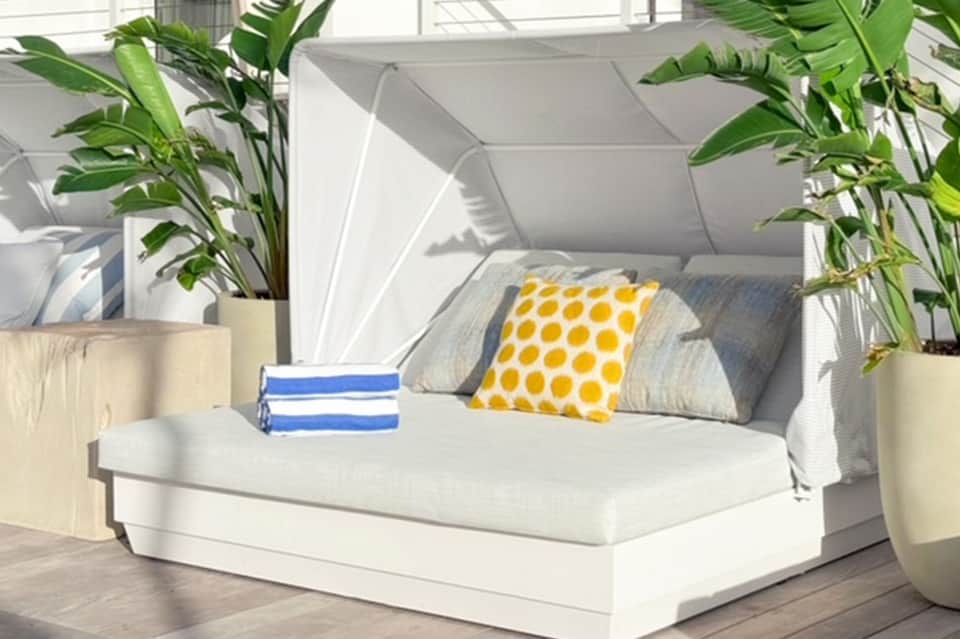 Modern bedroom with white bed, yellow polka dot pillow, potted plants, and sailboat art