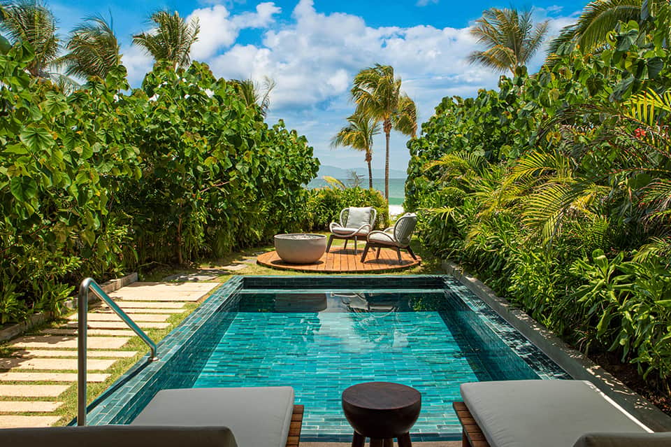 Private beachfront lap pool bordered by lush tropical vegetation with ocean view
