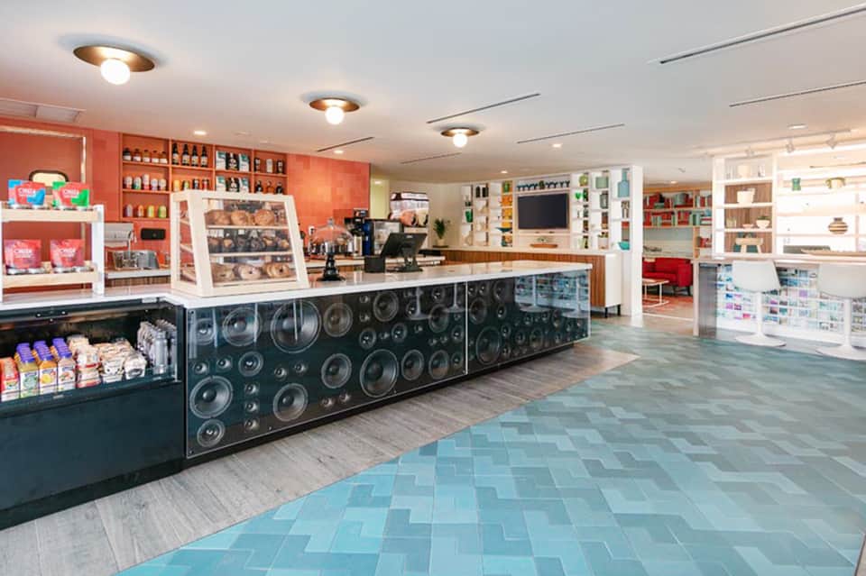 Colorful resort lobby with front desk, shelving displays, and orange and teal accent colors