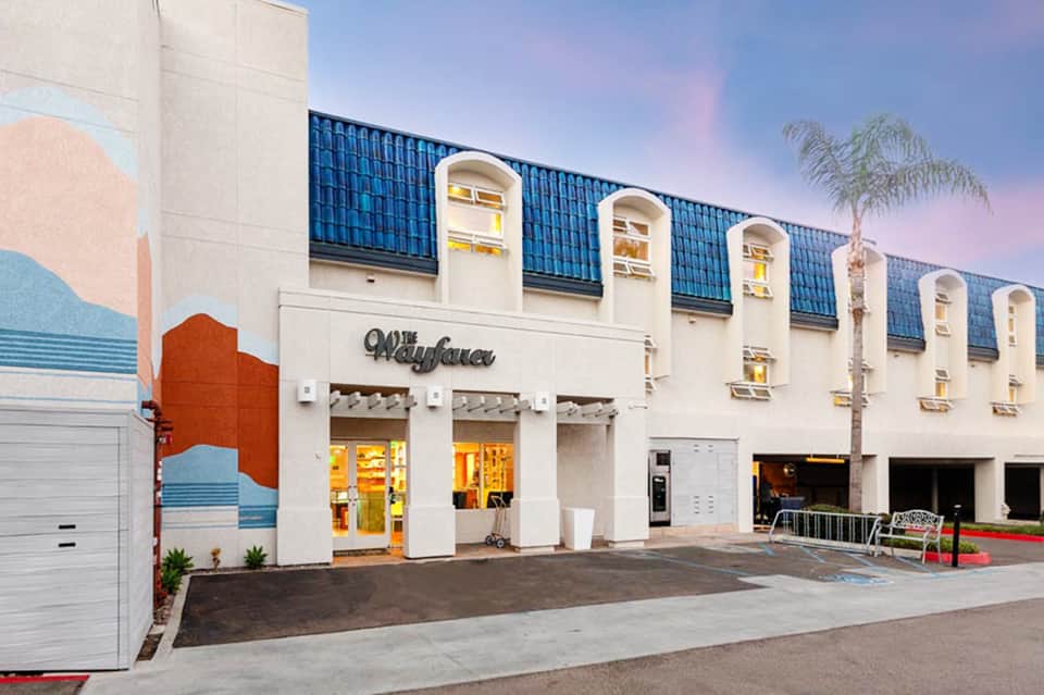 Retro-style beachside building with cream facade, blue roof detail, and palm tree
