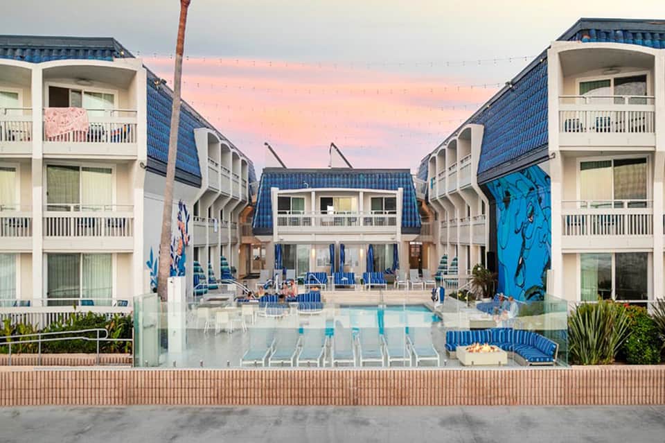 Beachfront resort courtyard at dusk with blue architectural features, pool, and pastel sky