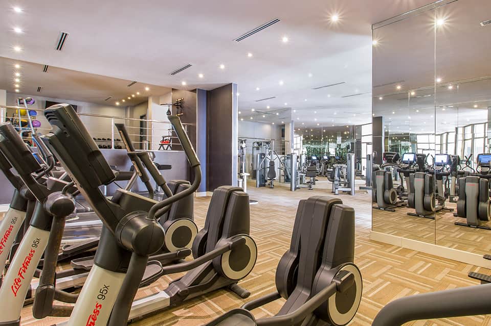 Modern fitness center with cardio equipment, mirrors, and recessed lighting