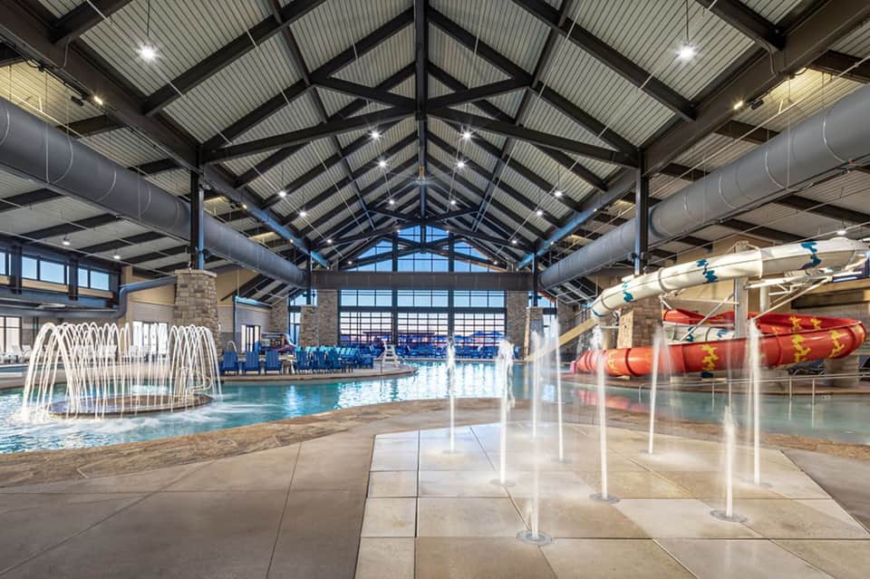 Indoor water park with indoor pool, fountain, waterslides, and high ceiling