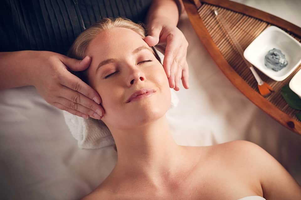 Woman receiving relaxing facial massage at luxury spa