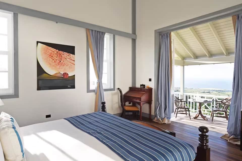 Coastal hotel bedroom with ocean view balcony, striped bedding, and modern furnishings