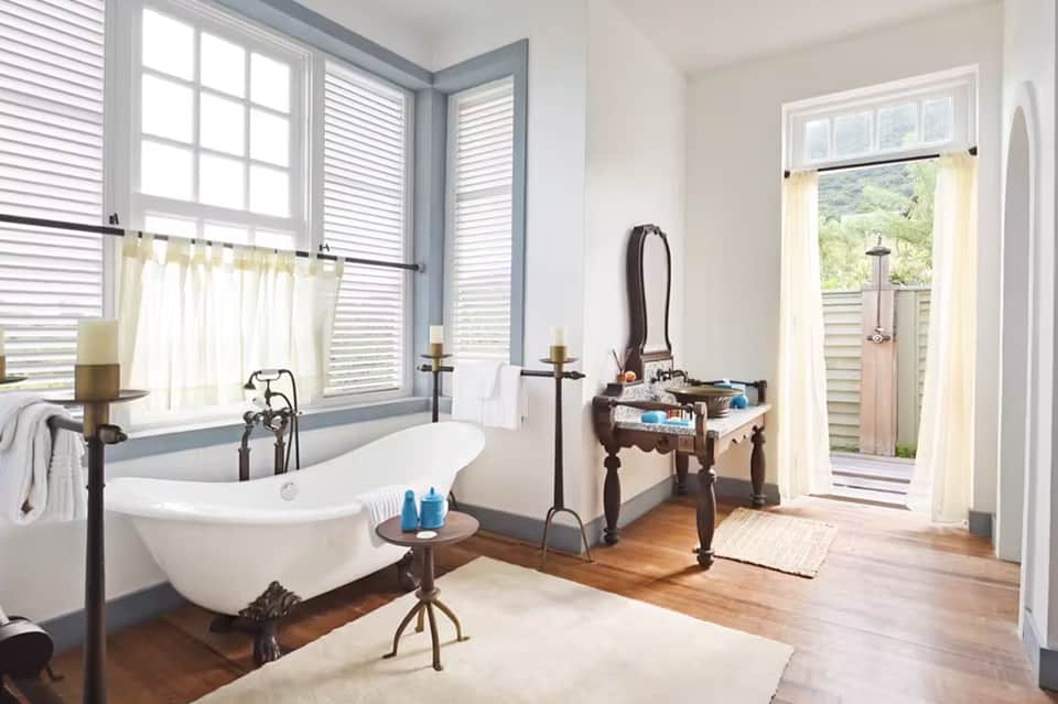 Luxury bathroom with freestanding tub, wood floors, blue-gray trim, and doors opening to terrace