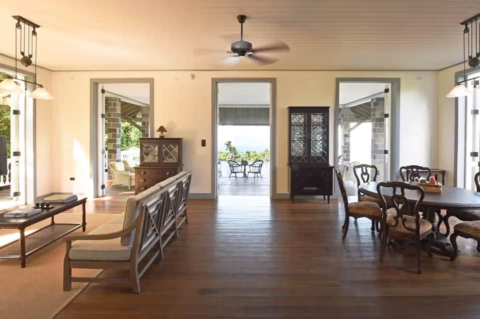 Elegant lakeside room with wood flooring, furniture, and open doors to waterfront deck
