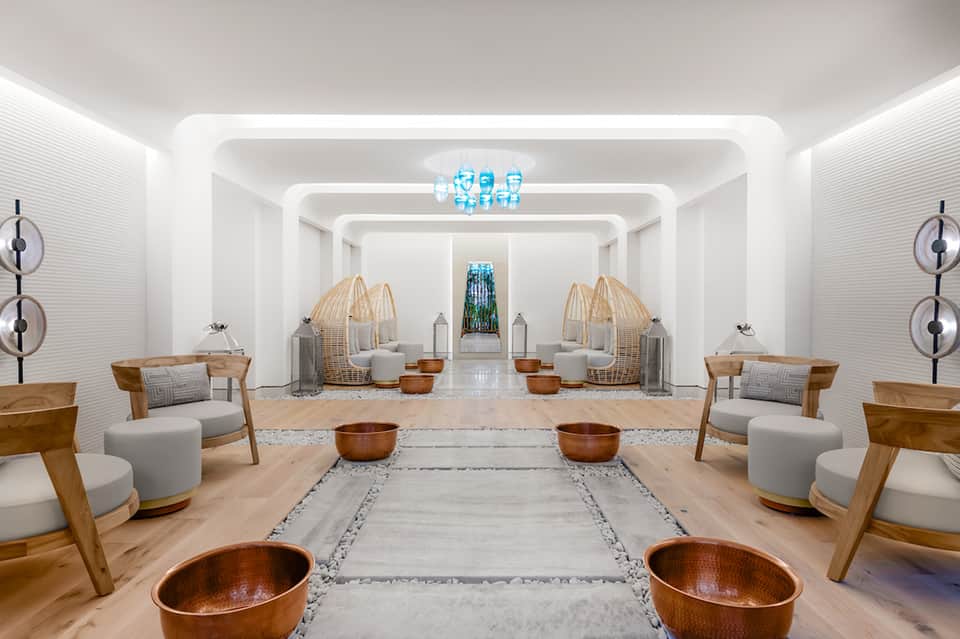 Modern spa wellness center with symmetrical seating, woven chairs, and minimalist white design