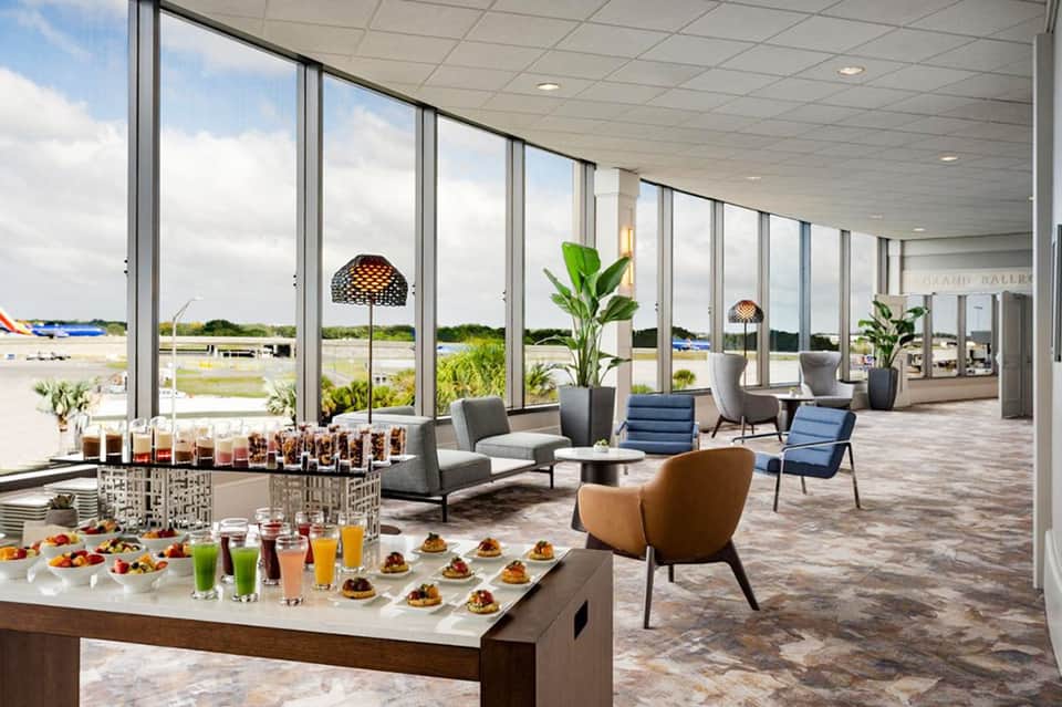 Modern resort lobby with expansive windows, lounge seating, refreshment bar, and scenic views