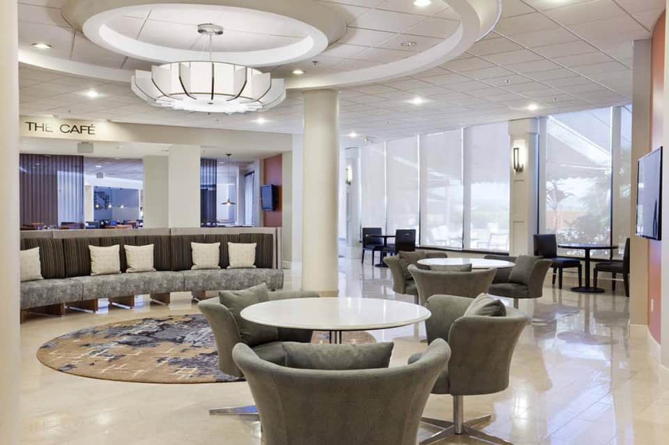 Hotel lobby with cafe seating, comfortable lounge furniture, round ceiling design, and large windows