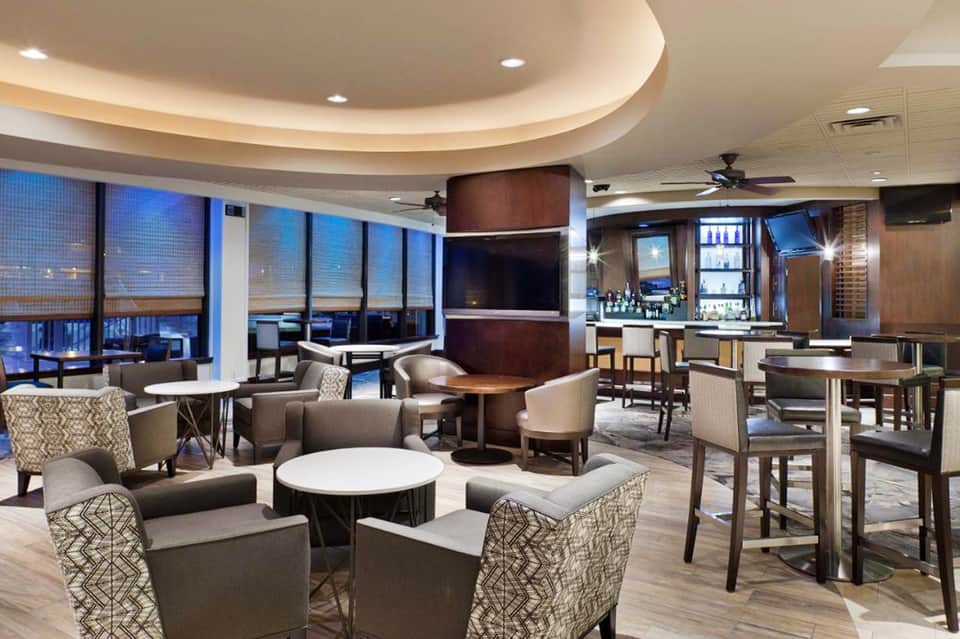 Elegant hotel lounge with comfortable seating, bar area, and expansive views through floor-to-ceiling windows
