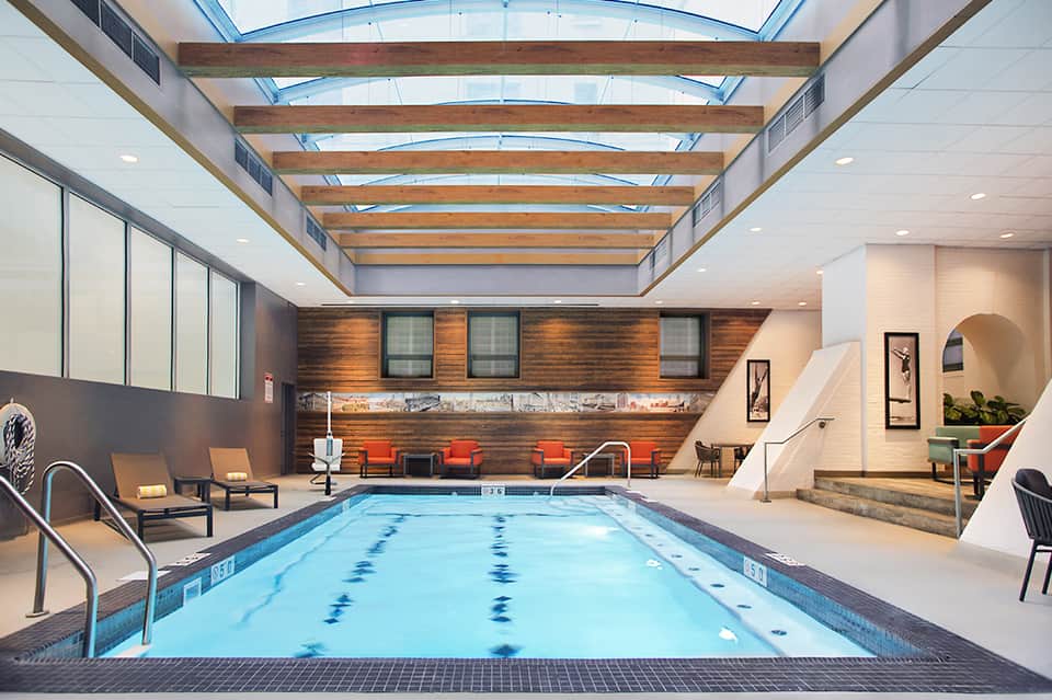 Indoor lap pool with skylights, wooden beams, and modern lounging area
