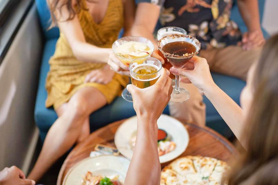 Group of people toasting with cocktails at a social gathering indoors