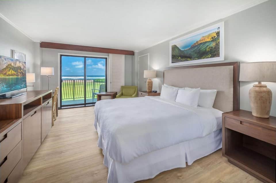 Modern hotel bedroom with ocean view balcony, king bed, and contemporary furnishings