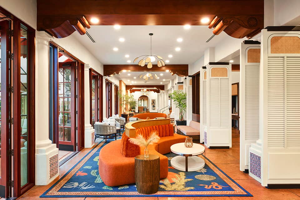 Stylish resort hallway with orange curved seating, wooden accents, and elegant lighting fixtures