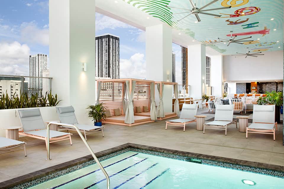 Rooftop pool deck with loungers, cabana, and city skyline views