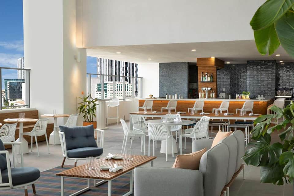 Upscale rooftop bar and lounge with city skyline views, modern seating, and wood accents