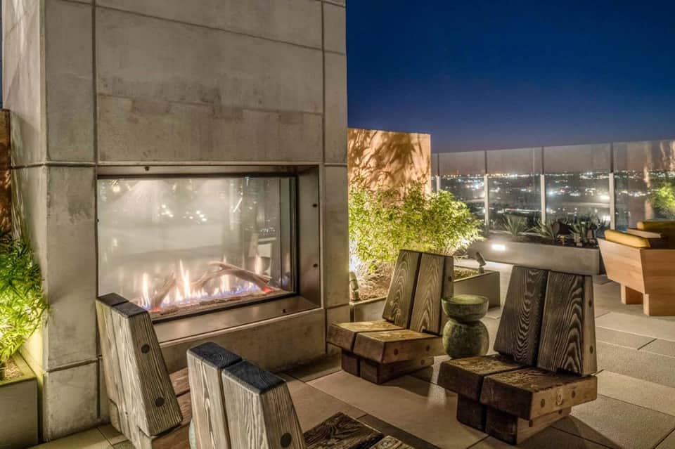 Modern rooftop patio with fireplace and city lights view at night