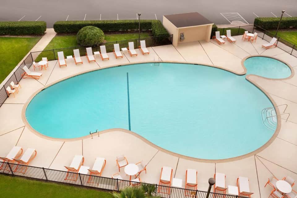 Aerial view of kidney-shaped swimming pool with lounge chairs and manicured landscaping