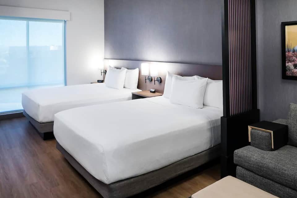 Modern hotel room with dual queen beds and minimalist dark decor