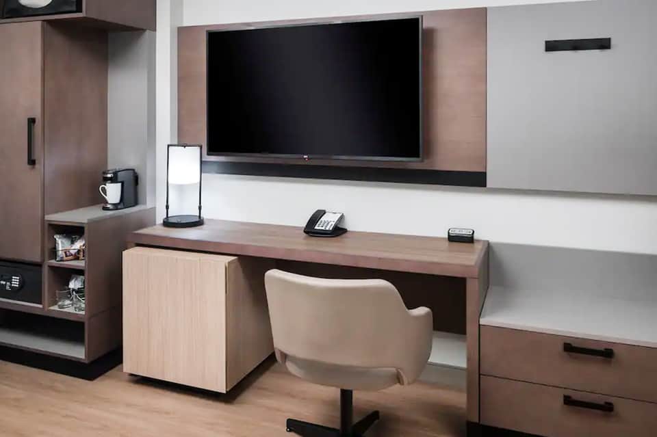 Modern hotel room with flat-screen TV, work desk, and contemporary furnishings