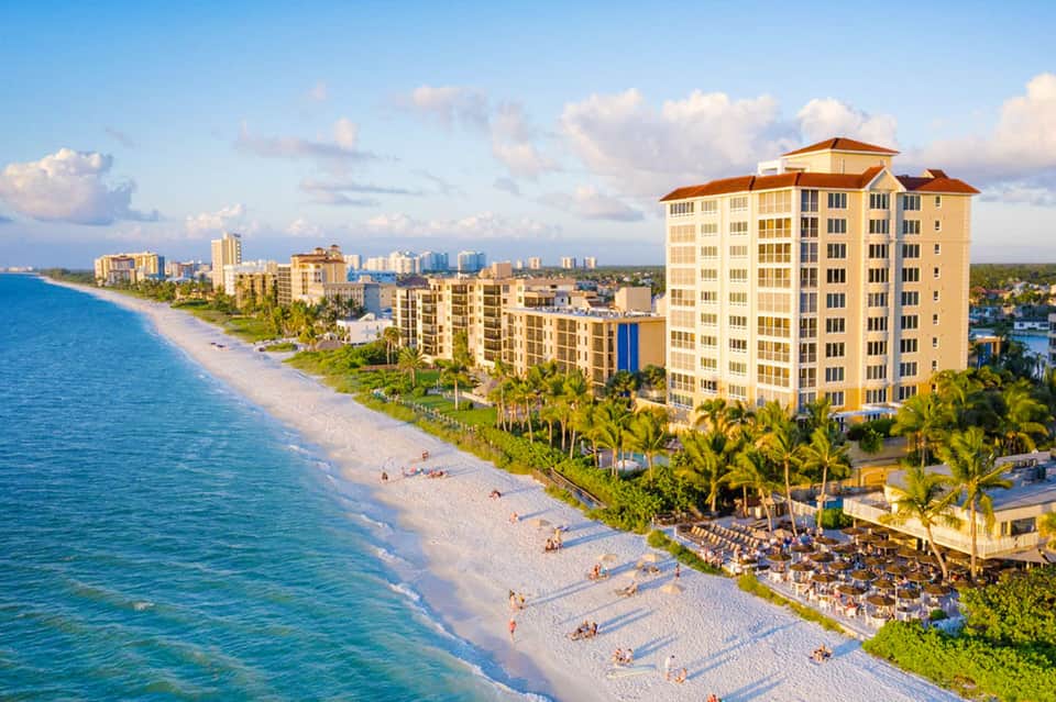 Beachfront resort with multi-story hotel buildings, sandy beach, and turquoise ocean waters
