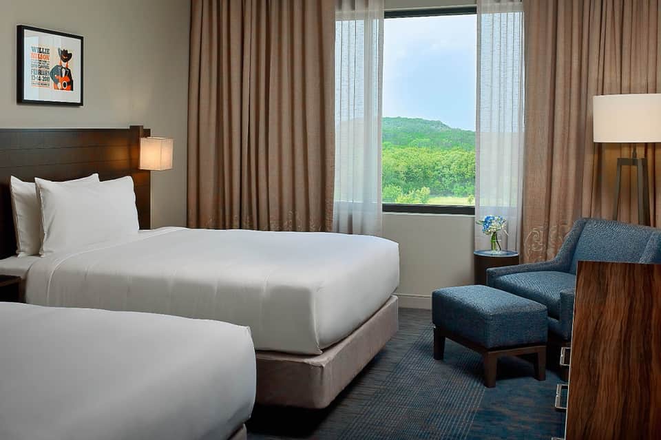 Hotel room with beds, seating area, and large window view of green mountains