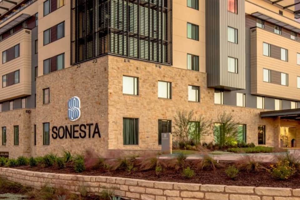 Modern hotel exterior with brick and tan siding featuring the Sonesta brand signage