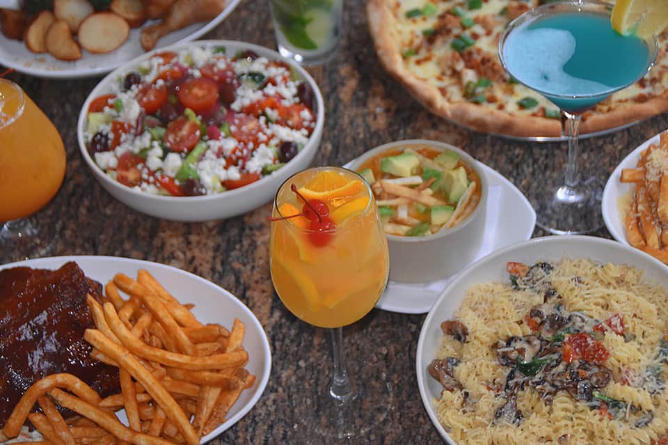 Overhead view of appetizers, entrees, cocktails, and dishes on a dining table