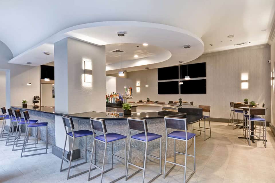 Contemporary hotel bar lounge with curved ceiling, bar seating, and modern furnishings