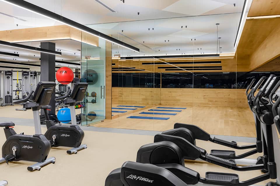 Modern fitness center with exercise equipment, mirrored walls, and wooden accents