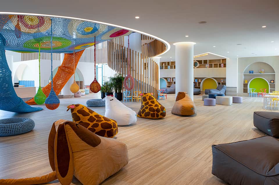 Modern kids club with colorful net installation, bean bags, and interactive play space