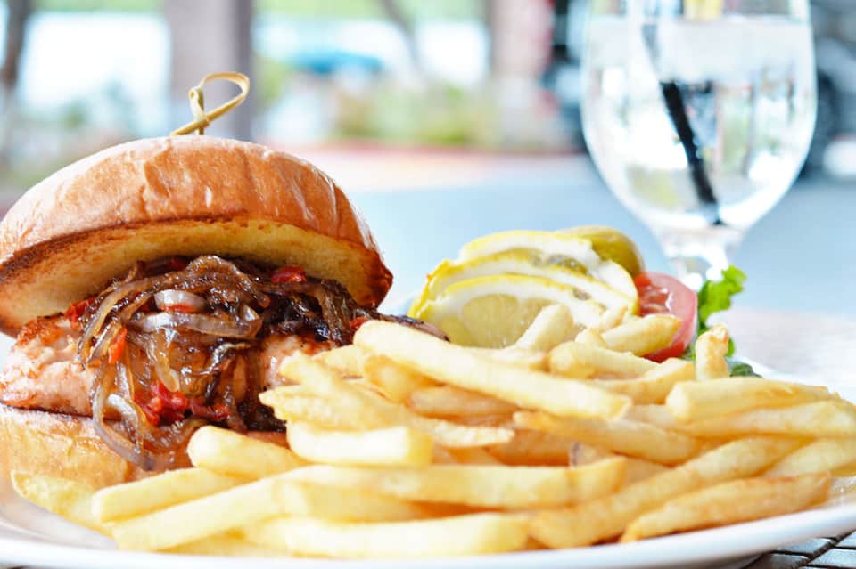 Pulled pork sandwich with caramelized onions and fries served with lemon on a plate