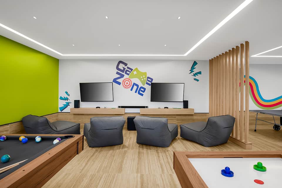 Modern gaming lounge with pool table, gaming screens, bean bag chairs, and colorful decor
