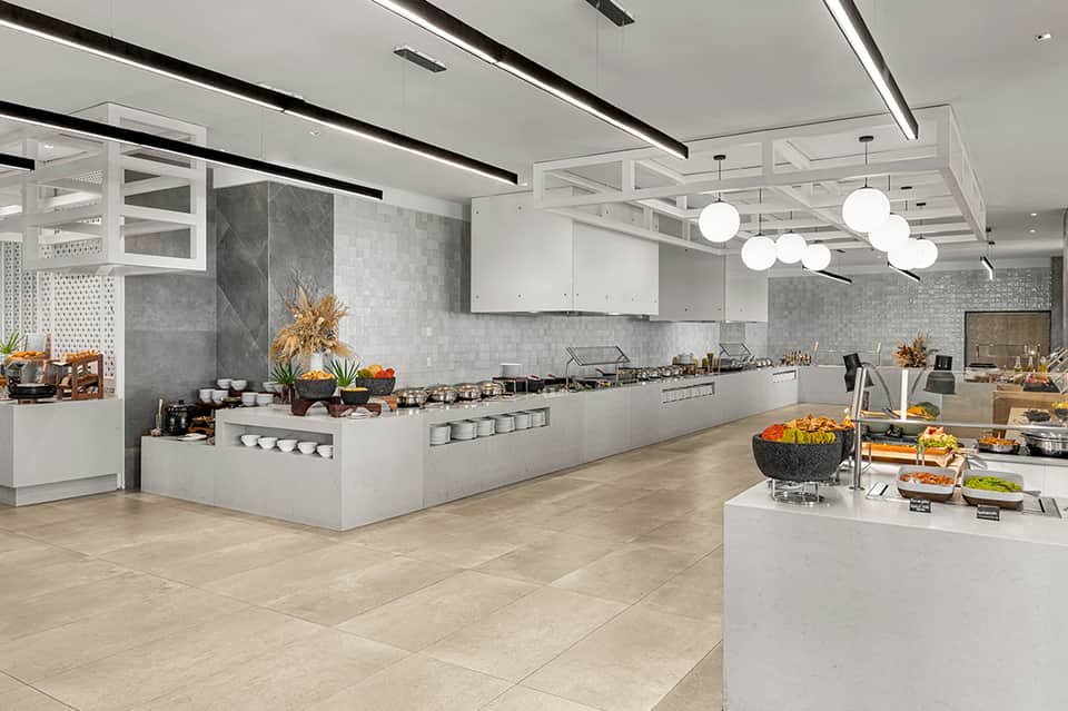Modern hotel kitchen with white cabinetry, gray tile backsplash, stainless steel appliances