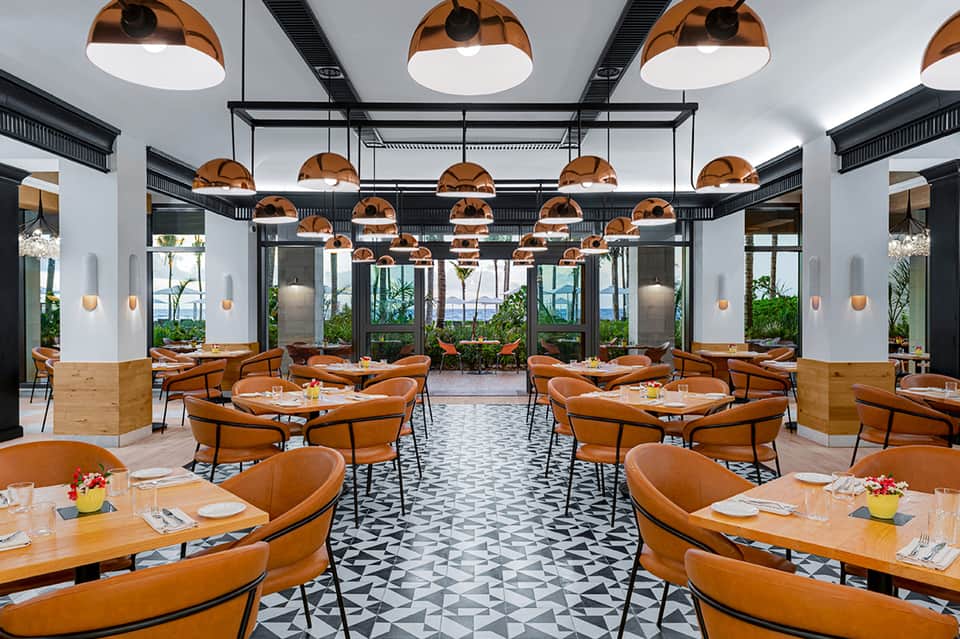 Contemporary restaurant with copper pendant lights, geometric tiles, and ocean-view windows