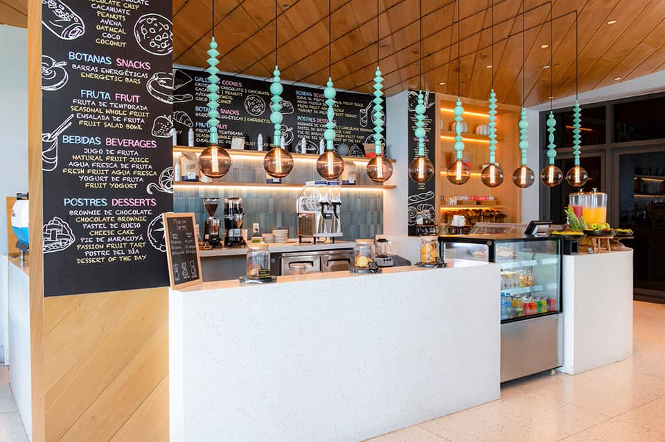 Bright cafe counter with turquoise pendant lights, wooden ceiling, and chalkboard menu board