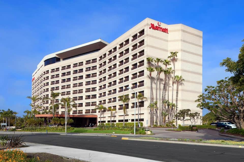 Multi-story Marriott hotel building with white exterior, palm trees, and clear blue sky