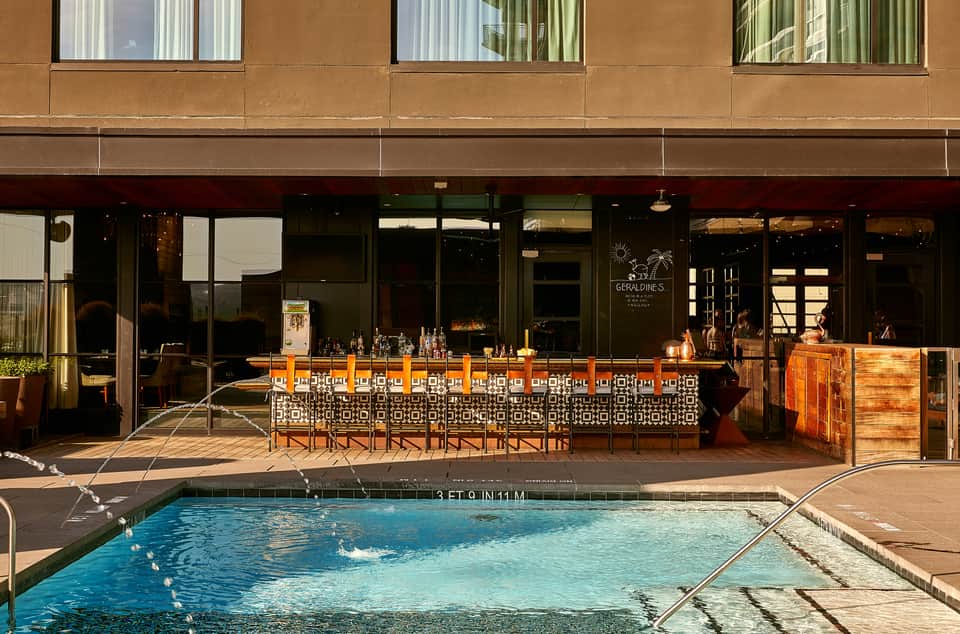 Elegant poolside lounge bar at dusk with decorative seating and modern building