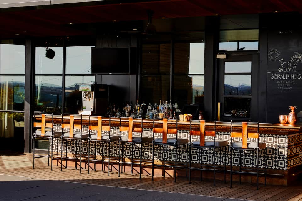 Outdoor bar with orange and black geometric design, mountain views, and modern black building facade